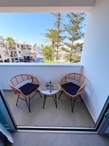 a balcony with two chairs and a table and a window at Living Boutique Apartments Adults Only in Ayia Napa