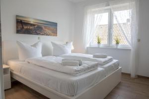 ein weißes Schlafzimmer mit einem großen Bett mit weißen Kissen in der Unterkunft Cuxhavener Straße 5/3 in Cuxhaven