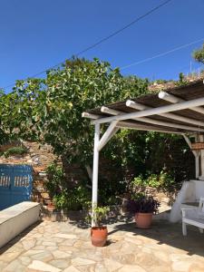 a wooden pergola with a bench and a chair on a patio at Thimari cottage in Andros in Agios Petros