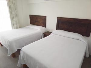 two beds in a hotel room with white sheets at Departamento Estrella de Mar in Puerto Vallarta