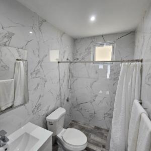 a white bathroom with a toilet and a sink at Latitude Adjustment in San Juan