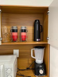 un placard avec un mixeur et des verres dessus dans l'établissement S3 - Lindo Apartamento em região central, à Foz do Iguaçu