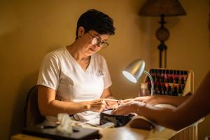 a woman sitting at a table cutting a persons nails at La Mision Loreto in Loreto