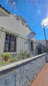 a white house with a fence in front of it at Casa Kolla - 2 bedrooms with private garage in downtown Salta in Salta
