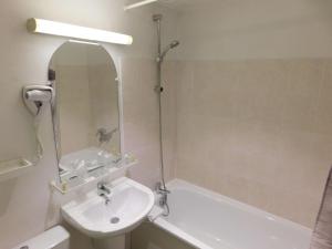 a bathroom with a sink and a tub and a mirror at Brit Hotel Argentan in Argentan +14 photos