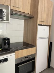 ラ・トリニテにあるappartement idéalement situéの白い冷蔵庫と電子レンジのあるキッチン