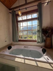 a bath tub in a room with a window at Serra a vista Chalé in Tiradentes +109 photos