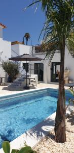 a villa with a swimming pool and a palm tree at Ferragudo Aqua Charme in Ferragudo