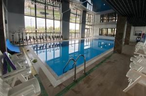 a large swimming pool with white chairs in a building at Gold Room in Szczecin
