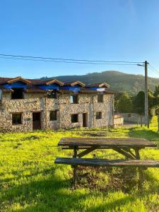 a wooden picnic table in front of a stone building at La Fontanina de Mario in Villaviciosa