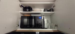 a black microwave in a cupboard with some dishes at Studette Sable & Mer cosy à 100m de la plage in Merville-Franceville-Plage