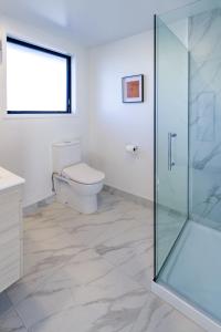 a bathroom with a toilet and a glass shower at Elegant Living by Middleton Park, Fully Equipped in Christchurch