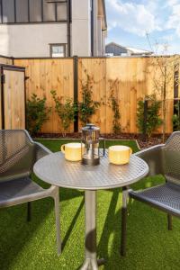 a patio with a table and chairs and a fence at Elegant Living by Middleton Park, Fully Equipped in Christchurch