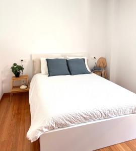 a white bed with blue pillows in a bedroom at Apartamento Estrellas de Mar in Ribeira