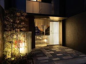 a building with a gate in front of it at night at MUSUBI HOTEL Kyoto Shijo-Omiya in Kyoto