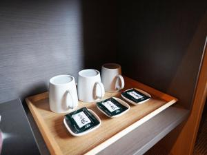 un vassoio di legno con tre tazze sopra di MUSUBI HOTEL Kyoto Shijo-Omiya a Kyoto