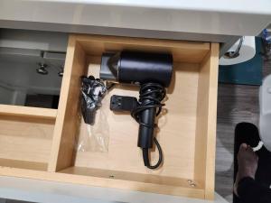 a hair dryer in a drawer of a desk at Cozy suite near Hospital, Stadium, Airport & RCMP in Regina