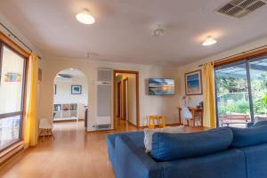 a living room with a blue couch and a table at 25 Elizabeth Crescent in Carrickalinga