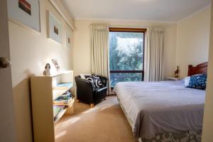 a bedroom with a bed and a chair and a window at 25 Elizabeth Crescent in Carrickalinga