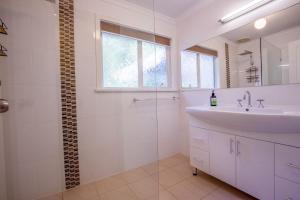 a white bathroom with a sink and a shower at 25 Elizabeth Crescent in Carrickalinga +10 photos