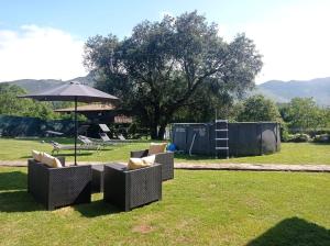 a group of chairs and an umbrella in a field at El Nogal de Pría in Garaña