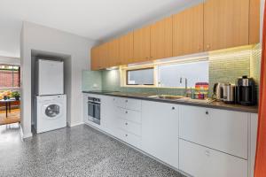 a kitchen with white cabinets and a washer and dryer at Convenient Bayside Living at the Edge of the City in Melbourne