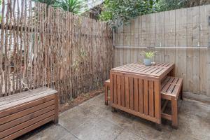 a patio with two benches and a wooden fence at Convenient Bayside Living at the Edge of the City in Melbourne
