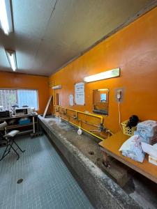 an orange room with a sink and a desk at やどバンブー in Hateruma