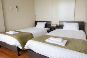 a room with two beds with towels on them at 20C Ryukyu in Nakijin