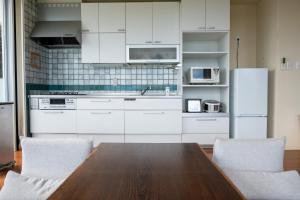 a kitchen with a wooden table and white appliances at 20C Ryukyu in Nakijin
