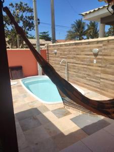 a hammock sitting next to a swimming pool at Casa de praia em Cabo Frio in Cabo Frio