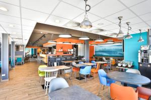 a restaurant with tables and chairs in a cafeteria at Kyriad Pontarlier in Pontarlier