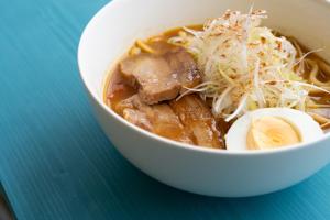 a bowl of soup with meat and egg on a blue table at 20C Ryukyu in Nakijin