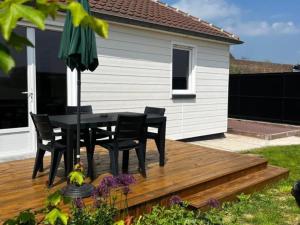 une table et des chaises noires sur une terrasse en bois dans l'établissement Gîte de Charme avec Jardin Privé, Proche de Lille et Hazebrouck, Idéal pour Familles et Cyclistes - FR-1-510-209, à Haverskerque