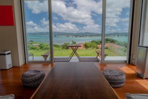 a dining room with a table and large windows at 20C Ryukyu in Nakijin