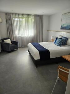 a bedroom with a large bed and a chair at Ballina Colonial Motel in Ballina