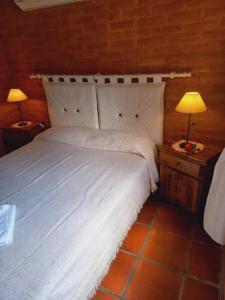 a bedroom with a large white bed with two lamps at Casa El Tabaquillo in Nono
