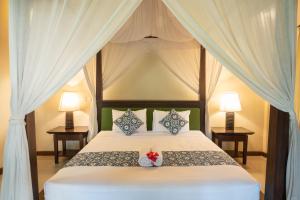 a bedroom with a canopy bed with two lamps at Villa Unique in Ubud