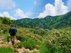 白山市にあるSDGs BASE AQUA PLUSのバックパックを背負って山道を歩く男性