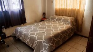 a bedroom with a bed with a brown and white comforter at Acogedora Casa Completa con jacuzzi privado in Quito