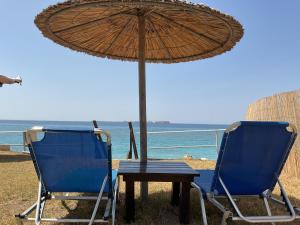 two chairs and a table with an umbrella on the beach at Kefalonia Beach Hotel & Bungalows in Lixouri