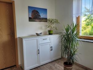 a white cabinet in a room with two potted plants at Bei Mallok's in Drebach +23 photos