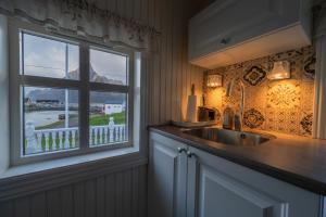 a kitchen with a sink and a window at Olenilsøya Mini Villa in Reine