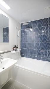Un baño con bañera, lavabo y espejo. en Wecostay Myeongdong, en Seúl