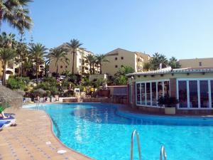 a pool at a resort with palm trees and buildings at Macdonald Doña Lola Resort in La Cala de Mijas