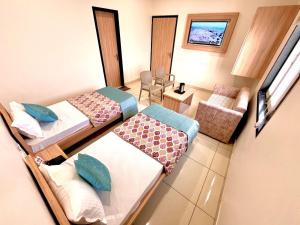 a small room with two beds and a chair at Hotel Rajvi Residency A Unit Of Jas Hotels And Resorts in Bikaner