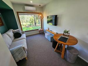 a living room with a couch and a table at Tuckers Lane Boutique Accommodation in Rothbury
