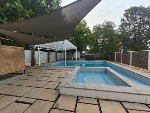 a swimming pool with an awning on a patio at Malgudi Farms in Bengaluru +49 photos