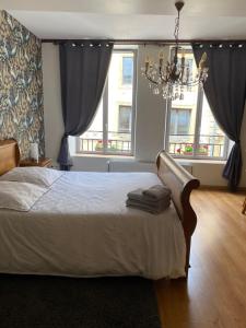 sypialnia z łóżkiem z żyrandolem i 2 oknami w obiekcie La Chambre d'Angèle w mieście Sedan