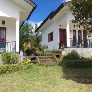 a white house with a yard in front of it at Shila Bungalow in Kelimutu